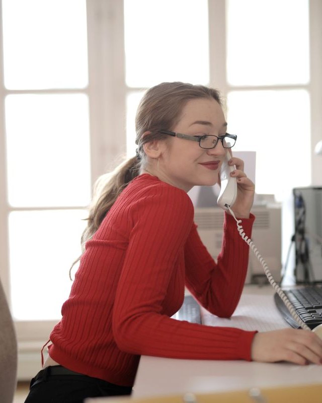 A smiling agent answering the phone at her desk